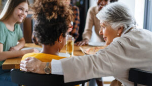 older women with her arm around a young women talking at a table with family | Honor Credit Union