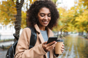 women looking at a cell phone and holding a coffee cup | Honor Credit Union