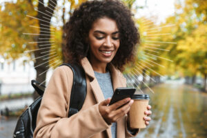 women looking at a cell phone and holding a coffee cup | Honor Credit Union