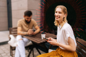 women holding a cell phone smiling sitting at a table with a man looking at his phone | Honor Credit Union