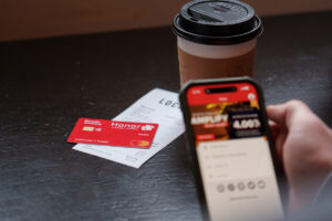 coffee cup, Local Cafe receipt with an Honor debit card on top. Cell phone with the Honor app | Honor Credit Union