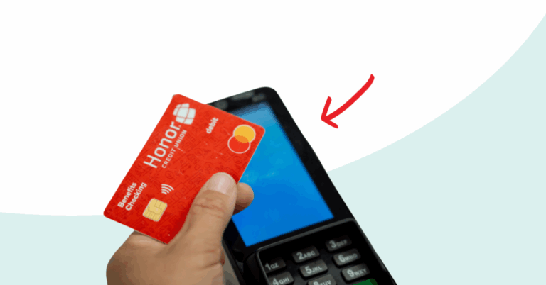 hand holding an Honor Benefits Checking Debit card in front of a card reader