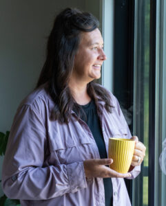 Honor member Julie, holding a coffee cup looking out the window | Honor Credit Union