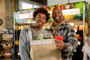 father and son holding groceries holding an Honor debit card | Honor Credit Union