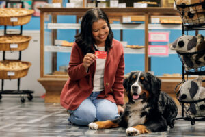 women holding a Honor Benefits Checking card kneeling next to her dog | Honor Credit Union