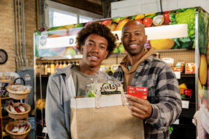a father and son hold an honor card and groceries | Honor Credit Union