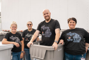 photo of shred day event at Honor operations center, Honor team member in a recycling bin and other team members standing next to him | Honor Credit Union