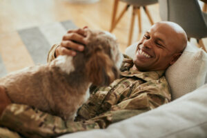 Happy military man enjoys with his dog at home | Honor Credit Union