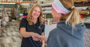 Smiling store employee shakes hands with a customer at the checkout counter in a shop. | Honor Credit Union
