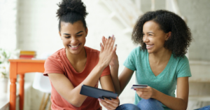 young women looking at an ipad giving a high five | Honor Credit Union