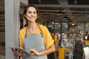 women store owner in an apron holding an ipad | Honor Credit Union