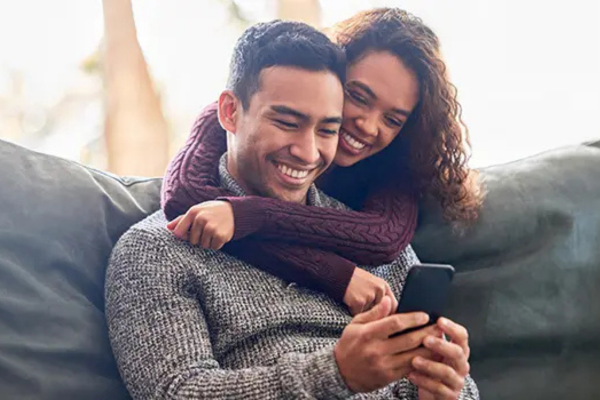 couple hugging looking at a cell phone