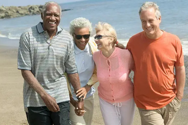 two couples retired enjoying a walk on the beach