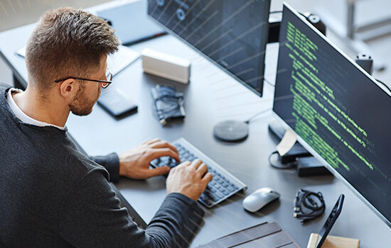 man on computer looking at code | Honor Credit Union | Honor Credit Union