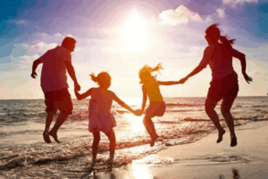 family jumping near the water at a beach | Honor Credit Union