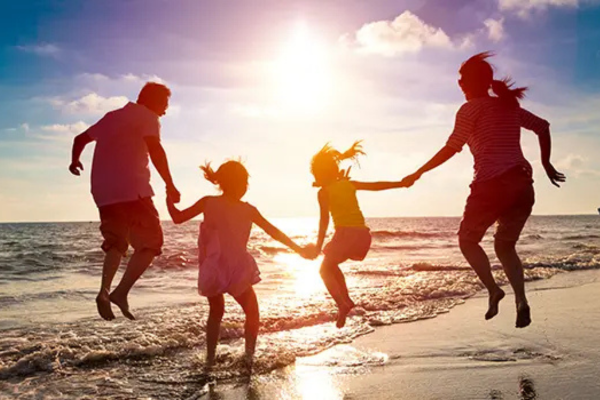 family jumping near the water at a beach