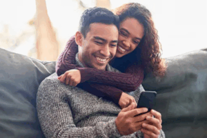 man and woman sitting together looking at a phone and smiling | Honor Credit Union