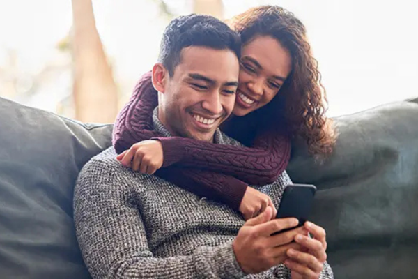 man and woman sitting together looking at a phone and smiling