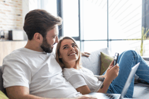 Couple on the couch looking at a cell phone | Honor Credit Union
