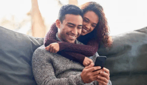 man and woman sitting together looking at a phone and smiling | Honor Credit Union
