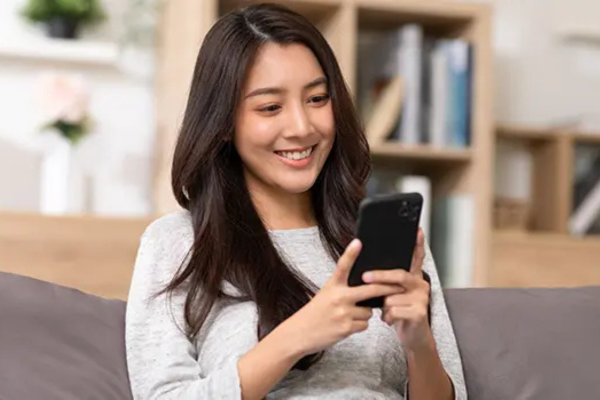 woman sitting on a couch looking at a mobile phone