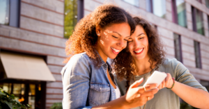 two women looking at a phone smiling | Honor Credit Union