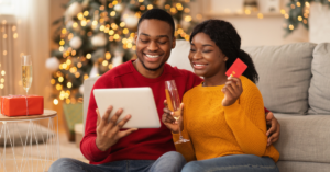 couple on ipad shopping online with Christmas tree in their living room | Honor Credit Union