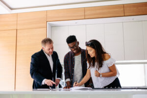 Couple signing a contract documents while standing inside a house with real estate agent | Honor Credit Union