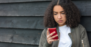 young women looking concerned at her cell phone | Honor Credit Union