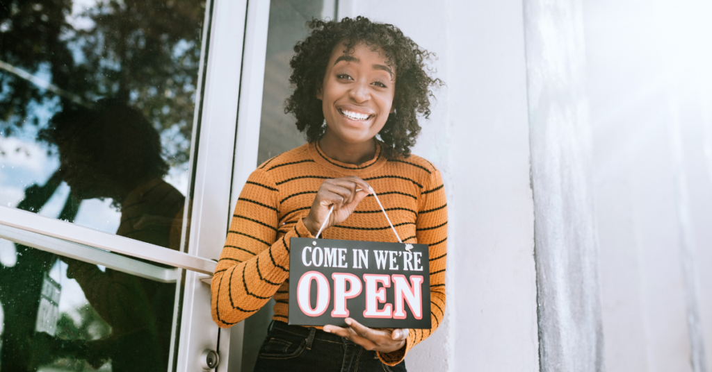 women with an open sign in front of her business | Honor Credit Union
