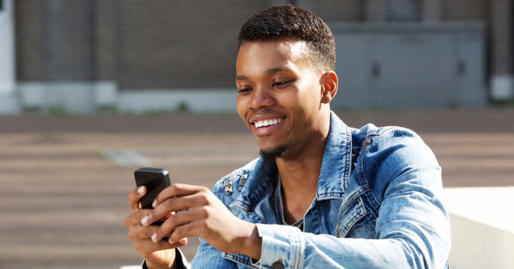 man look at cell phone smiling | Honor Credit Union
