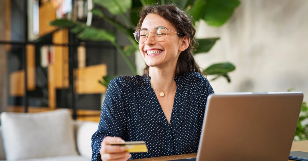 women on laptop holding her credit card smiling