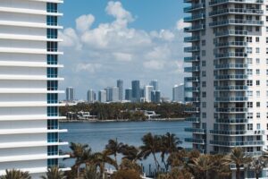 Waterway framed by two white modern apartment towers, with palm trees in the foreground and a distant city skyline. | Honor Credit Union