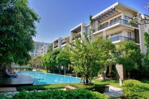 Resort-style residential complex with a long swimming pool, lounge chairs, and landscaped trees. | Honor Credit Union
