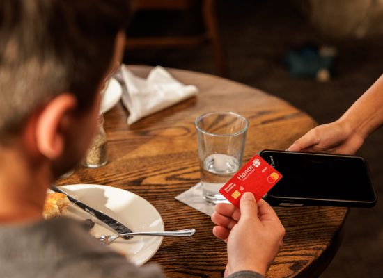 Checking-Accounts-Honor1 man paying a dining bill with his Honor credit card tap and pay