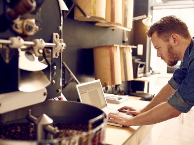 Business owner of a coffee roastery checking his laptop Small business owner of roastery checking his laptop