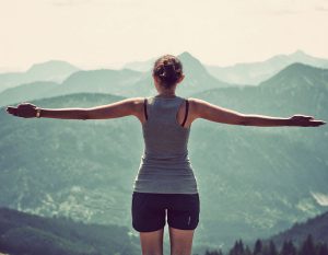 savingsMountainB woman standing with her arms out looking at a mountain landscape